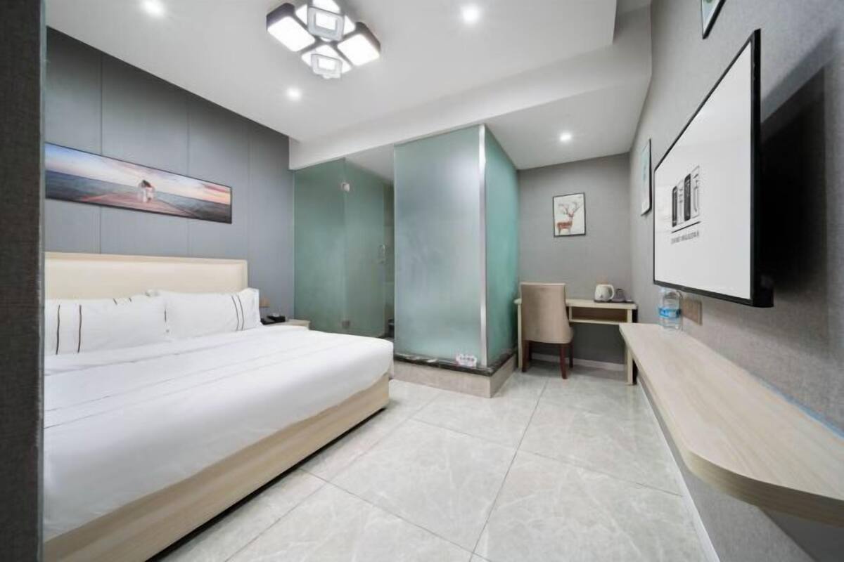 Ein modernes Hotelzimmer mit einem großen Bett, einem Schreibtisch und einem an der Wand befestigten Flachbildfernseher.