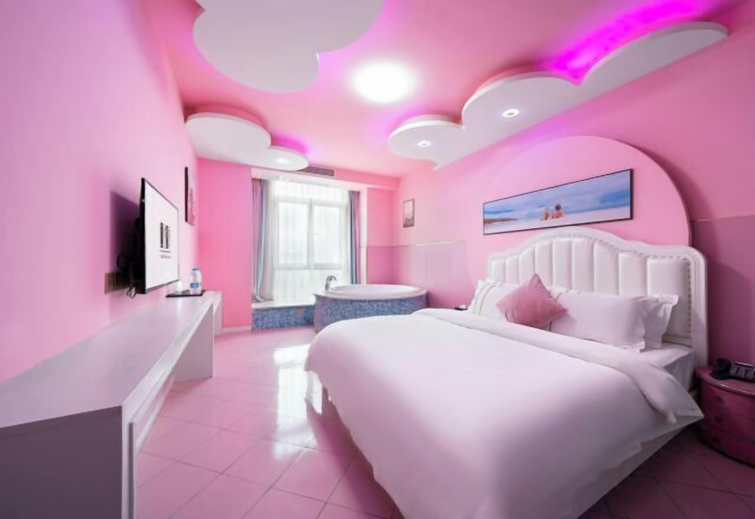 A pink-themed bedroom with a bed, a vanity, and a window.