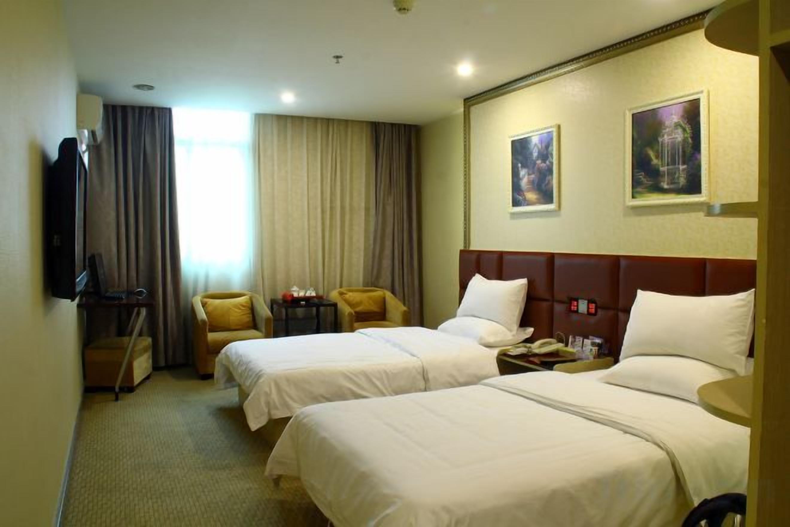 A hotel room with two beds, a TV, a desk, and a chair.