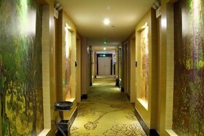 A hotel hallway with a carpeted floor, a trash bin, and a door at the end. - Quan Shan Hotel (Quanzhou)