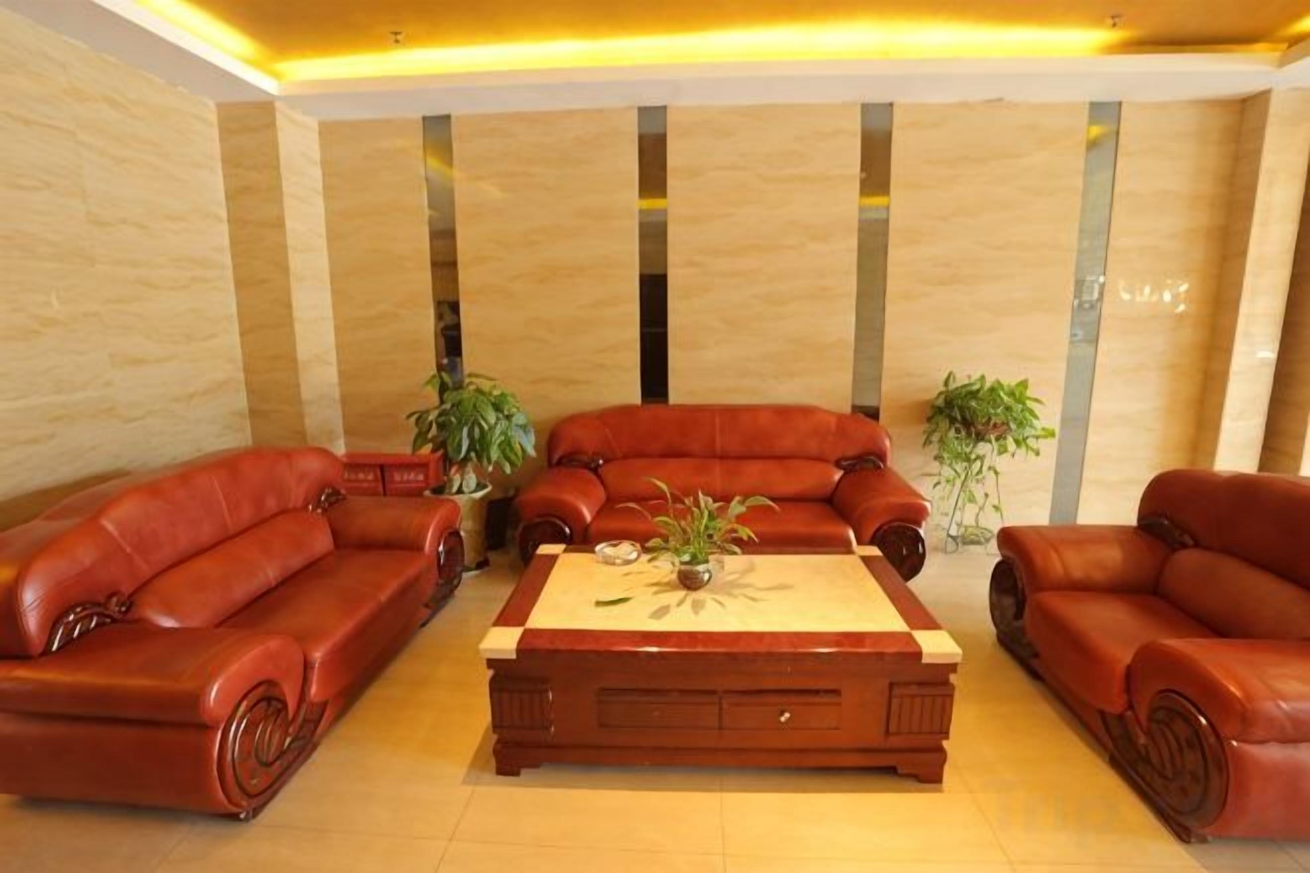 A lobby with leather sofas, a wooden coffee table, and potted plants.
