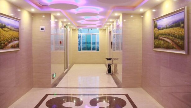 Hall d'hotel dal design moderno, con una parete divisoria centrale in vetro, pavimento a motivi decorativi e luci a soffitto.