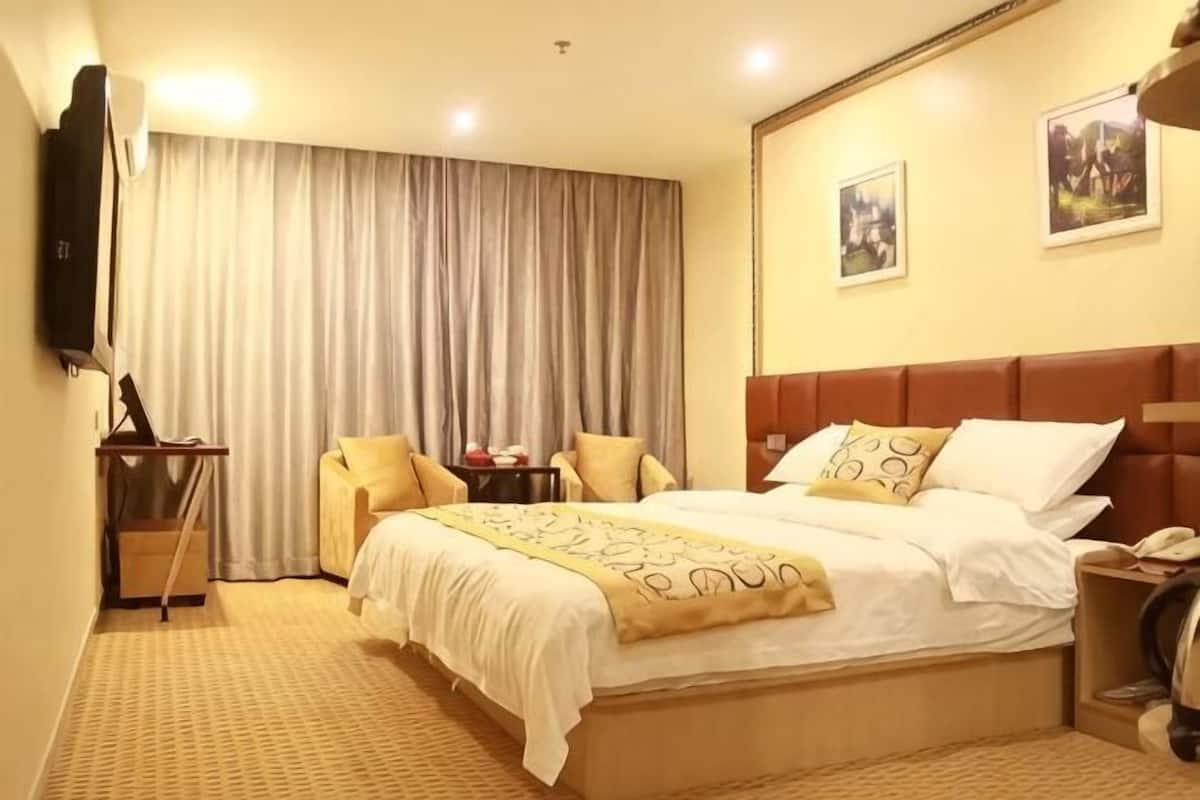 A hotel room with a bed, a television, a desk, and a chair.