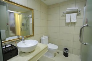 A bathroom with a white sink, a toilet, a glass shower enclosure, and a towel rack with towels. - Quan Shan Hotel (Quanzhou)