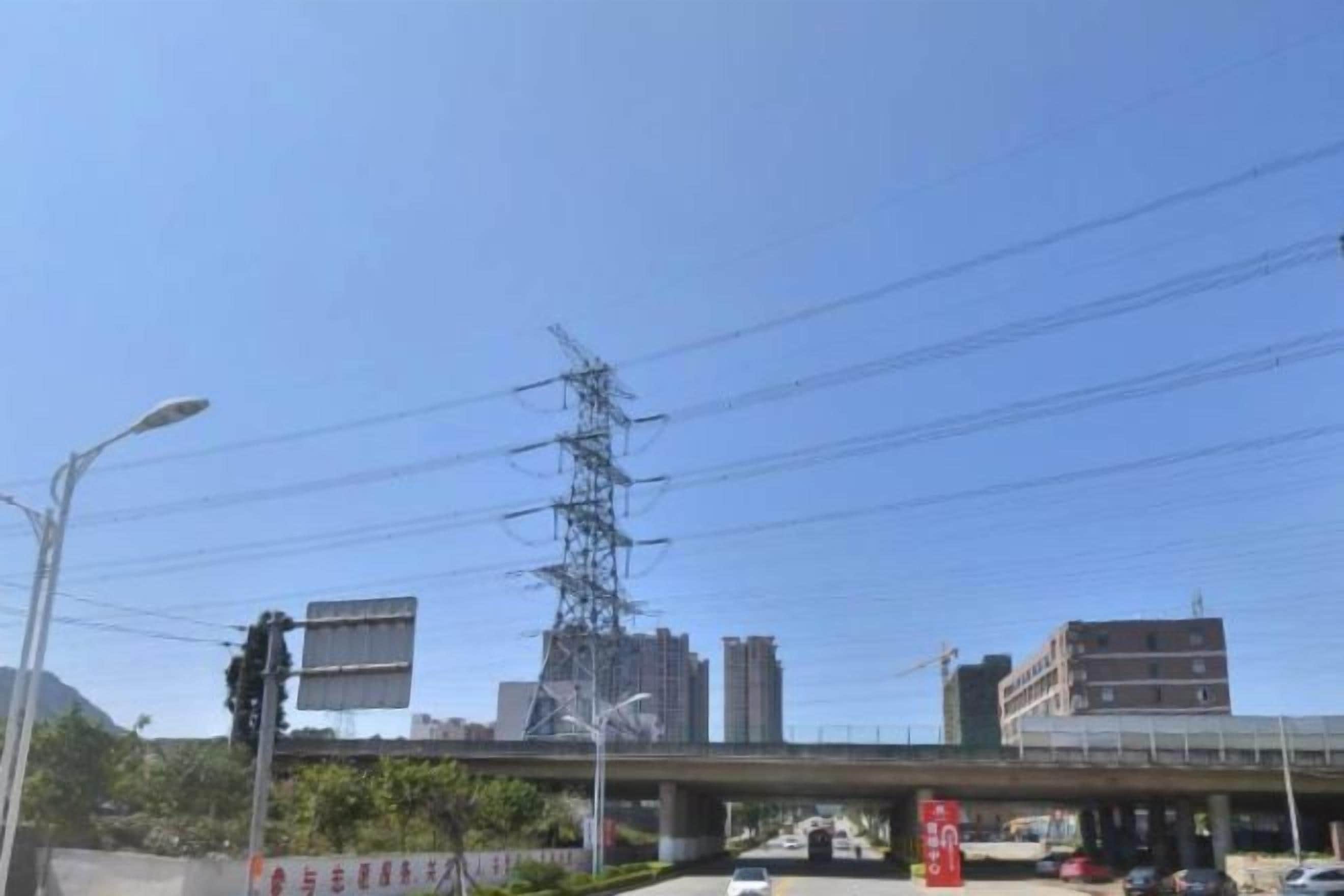 Cielo despejado con un puente, edificios y líneas de electricidad.