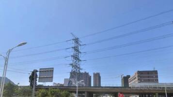 Cielo despejado con un puente, edificios y líneas de electricidad.