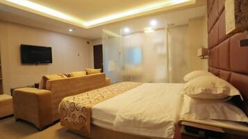 Ein Hotelzimmer mit Bett, Sofa, Fernseher und Glastrennwand.