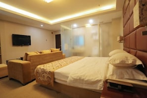 Una habitación de hotel con cama, sofá, televisión y un panel de vidrio.