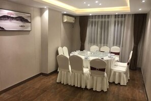 Un salón de conferencias con mesas redondas, sillas blancas y un cuadro en la pared.