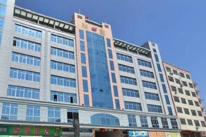 A multi-story building with a prominent blue and pink facade, multiple windows, and a visible storefront at the ground level. - Quan Shan Hotel (Quanzhou)