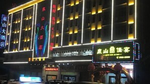 Un hotel con diversi piani, insegne illuminate e un cartello al neon ben visibile.