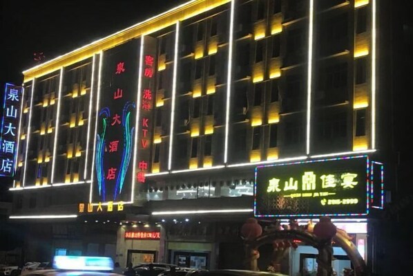 Ein mehrstöckiges Hotel mit beleuchteter Beschilderung und einer auffälligen Neonreklame.