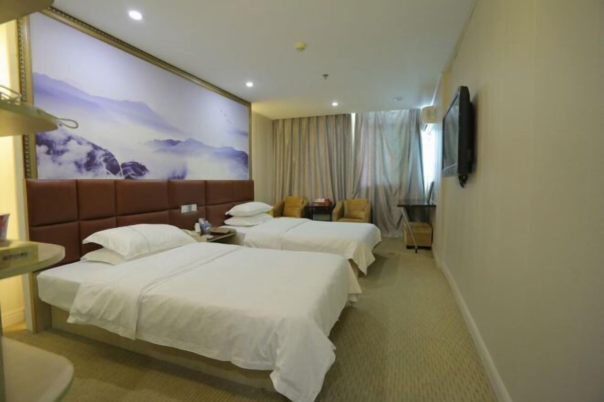 A hotel room with two beds, a large wall mural, a television, and a window with curtains.