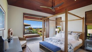 A four-poster bed with a view of the ocean, a wooden ceiling fan, and a large window with a view of the garden. - Panoramic Ocean Views From Private Gated Estate (Kaloa)