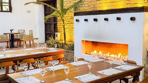 Um restaurante com parede de tijolos, lareira e mesas postas para refeições.