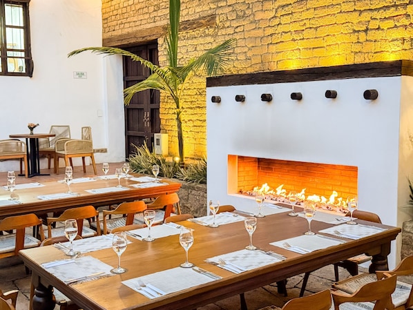 A restaurant with a brick wall, a fireplace, and tables set for dining.