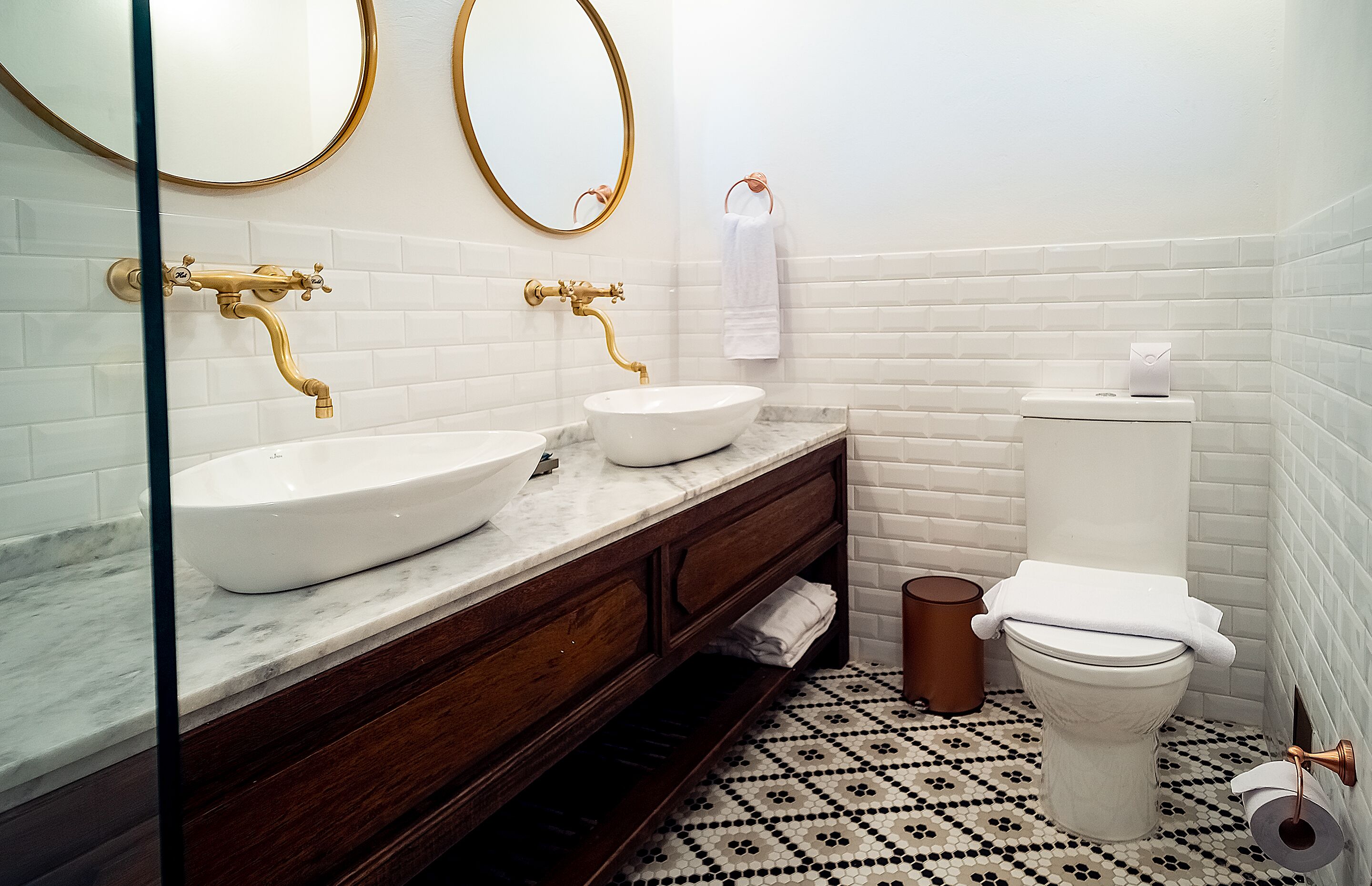 A bathroom with two sinks, a toilet, and a mirror.