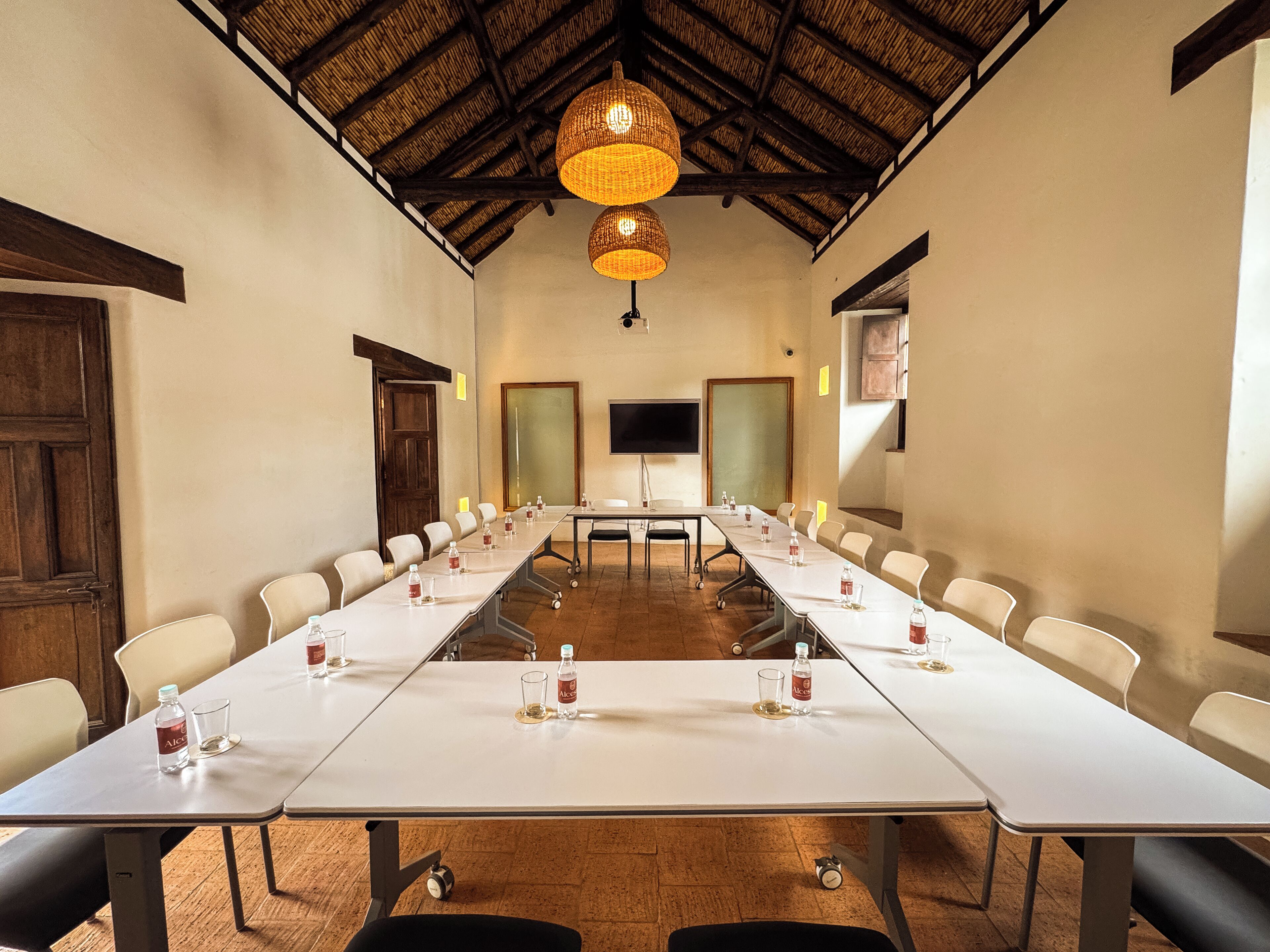 A conference room with a long table, chairs, a television, and a ceiling with woven light fixtures.