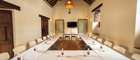 A conference room with a long table, chairs, a television, and a ceiling with woven light fixtures.