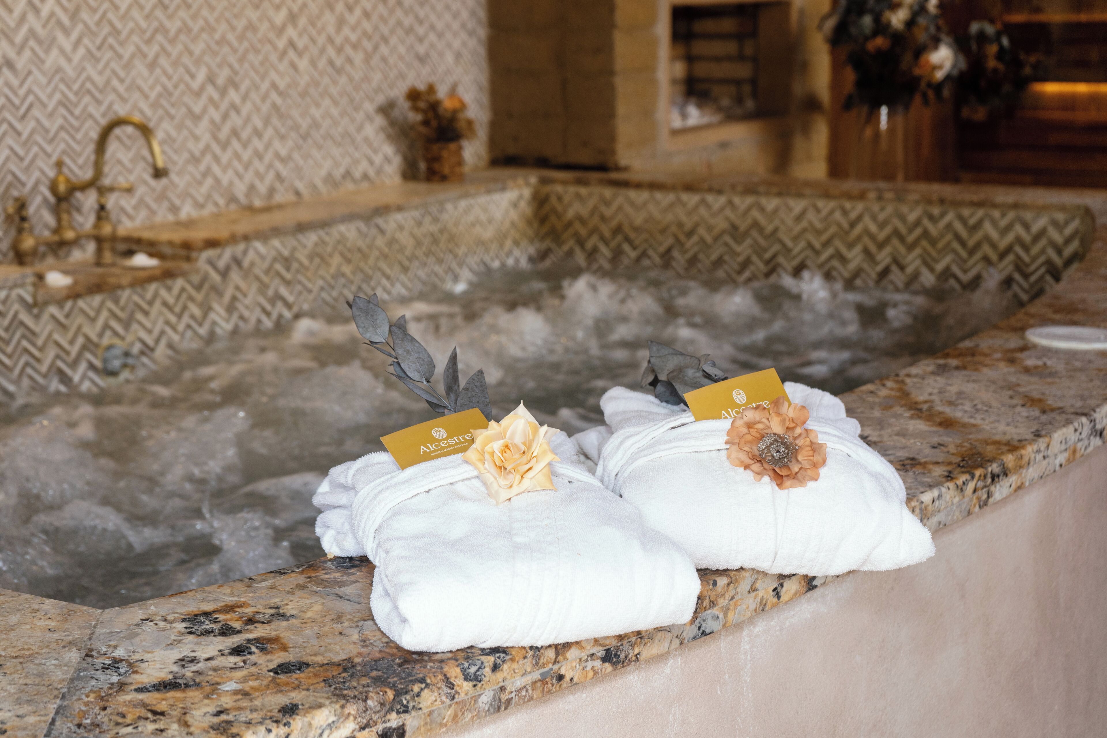 A spa area with a hot tub and towels with flower decorations and name tags.