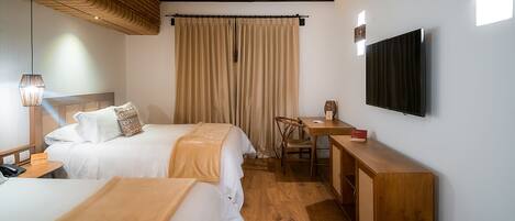 Habitación de hotel con dos camas, un escritorio, una silla, un televisor y techo de madera.