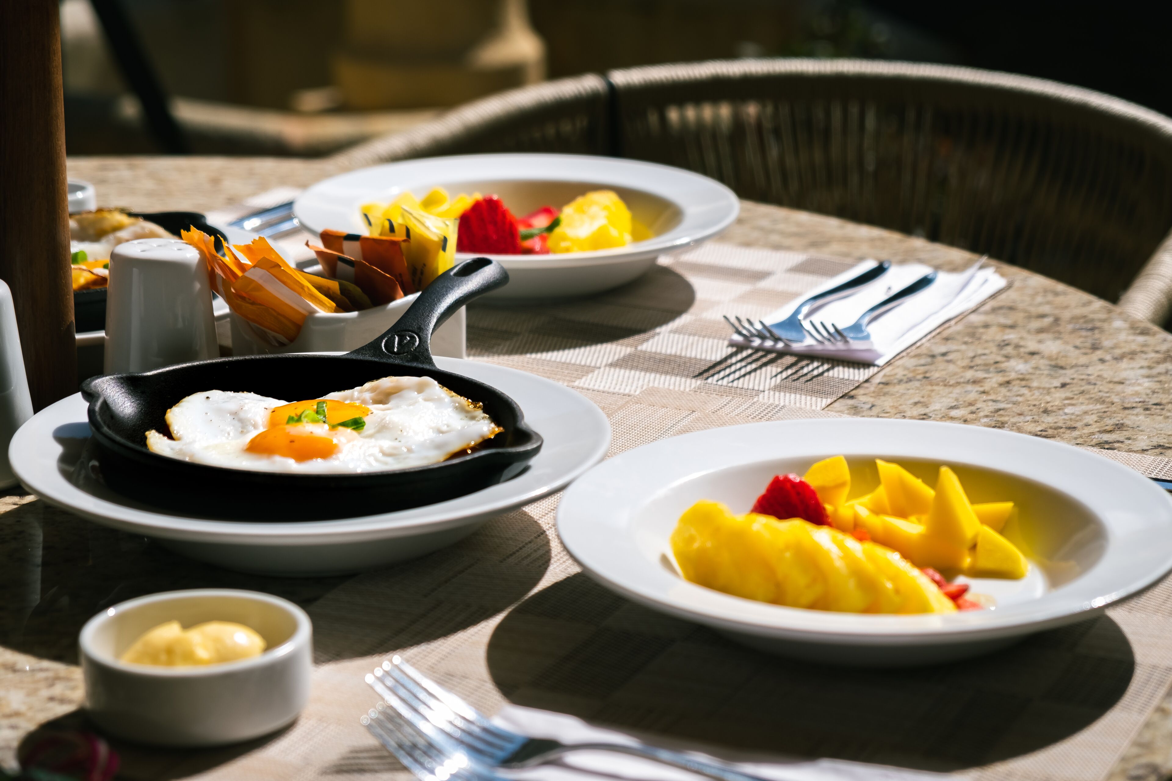A table set with plates of food, including eggs and fruit, and a small bowl of butter.