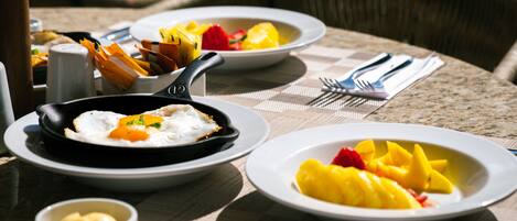A table set with plates of food, including eggs and fruit, and a small bowl of butter.
