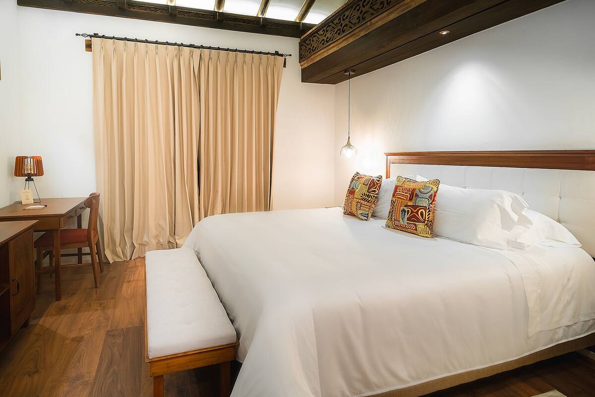 A bedroom with a large bed, a desk, and a chair.