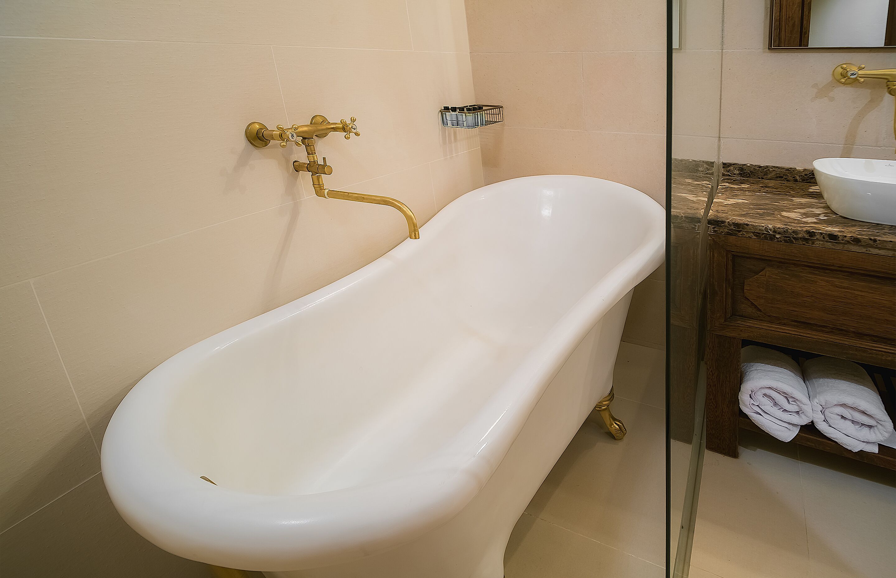 Un baño con una bañera blanca, un tocador de madera con un lavamanos y un perchero para toallas.