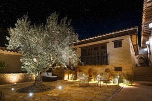 A courtyard with a large tree, outdoor seating, and a building with a tiled roof.