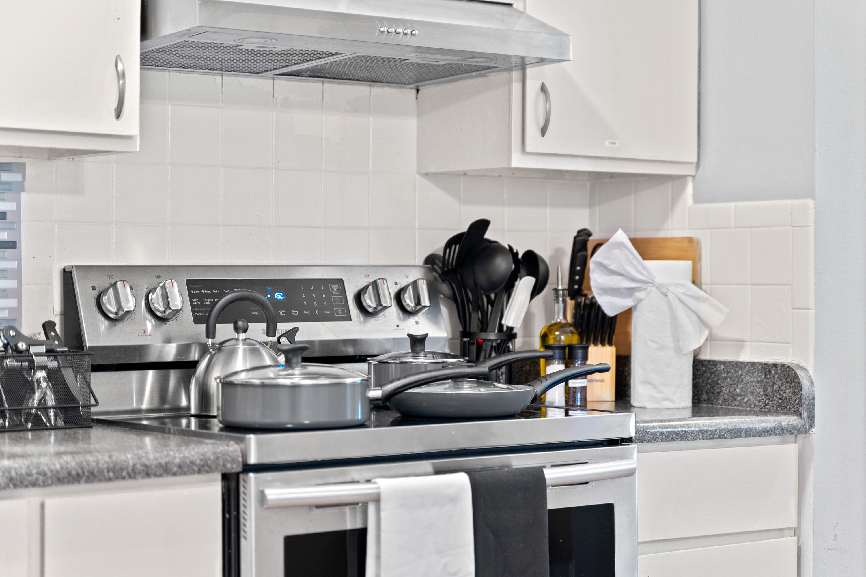 Una cucina moderna con elettrodomestici in acciaio inossidabile, tra cui un fornello e un forno, e un piano di lavoro in granito.