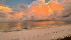 Une plage avec une mer calme et un ciel au coucher du soleil.