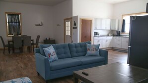 A living room with a blue sofa, a wooden coffee table, and patterned armchairs. - Private, quiet & beautiful second story with peek a boo water views (Milbridge)