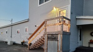 A two-story building with a wooden staircase and a small porch area. - Private, quiet & beautiful second story with peek a boo water views (Milbridge)