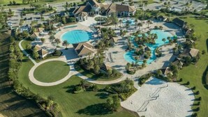 Vue aérienne d’un complexe hôtelier doté de plusieurs piscines, de terrains de golf et d’aménagements paysagers bien entretenus.