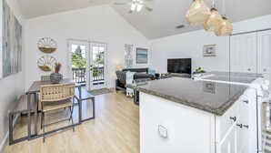 A spacious kitchen with a large island, a dining area with a wooden table and chairs, and a living area with a sofa and TV. - Modern Home in downtown Middletown! Walk to shops & restaurants! (Middletown)