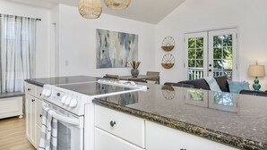 A modern kitchen with a large island, white cabinetry, and a dining area with a sofa and table. - Modern Home in downtown Middletown! Walk to shops & restaurants! (Middletown)