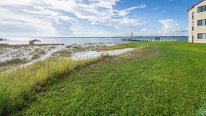 A grassy area with a view of a body of water and a pier extending into it. - Welcome to Paradise! (Navarre)