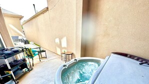 A hot tub in a covered outdoor area with a table and chairs nearby. - 10th St Manor + Walk to Stadium + Hot Tub + Game Garage + Sleeps 20 (Lubbock)