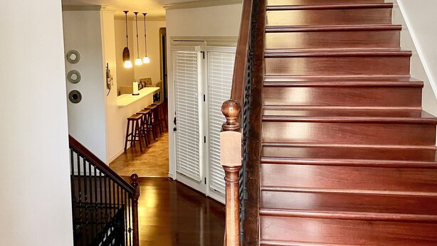 A wooden staircase with a handrail leading to a second-floor landing. - 10th St Manor + Walk to Stadium + Hot Tub + Game Garage + Sleeps 20 (Lubbock)