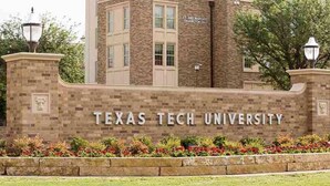 A stone wall with "Texas Tech University" written on it, surrounded by a flower bed and lamp posts. - 10th St Manor + Walk to Stadium + Hot Tub + Game Garage + Sleeps 20 (Lubbock)