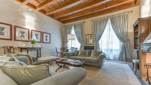 A cozy living room with a high wooden ceiling, a fireplace, and a dining area with a table and chairs. - Pontormo large apartment with fireplace in Oltrarno (Firenze)