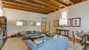 Un vaste salon doté d’un haut plafond en bois, d’une cheminée et d’un coin repas avec une table et des chaises.