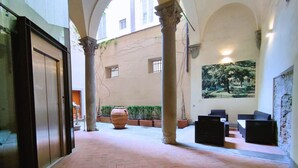 A spacious courtyard with a large planter, a mural, and a seating area. - Pontormo large apartment with fireplace in Oltrarno (Firenze)