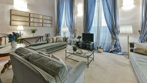 A spacious living room with a sofa set, a coffee table, and a television. - Caravaggio frescoed big loft in Oltrarno (Firenze)