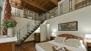 Un dormitorio espacioso con una cama grande, una escalera de madera y vistas al piso superior.
