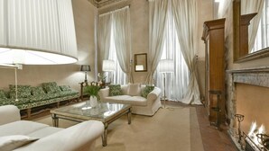 A spacious living room with a sofa set, a glass coffee table, and a fireplace. - Raffaello large apartment with fireplace in Oltrarno (Firenze)