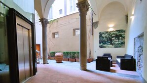 A spacious courtyard with a large planter, a mural, and a seating area. - Raffaello large apartment with fireplace in Oltrarno (Firenze)