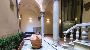 A courtyard with a large terracotta pot, stone benches, and a staircase with balustrades. - Raffaello large apartment with fireplace in Oltrarno (Firenze)