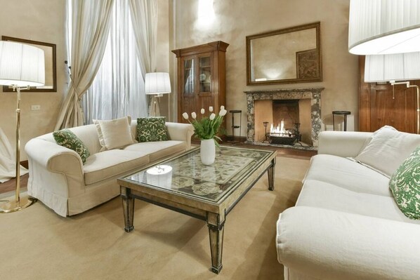 A spacious living room with two sofas, a glass coffee table, and a fireplace. - Spacious "Raffaello" apartment with a fireplace in the Oltrarno neighborhood (Firenze)